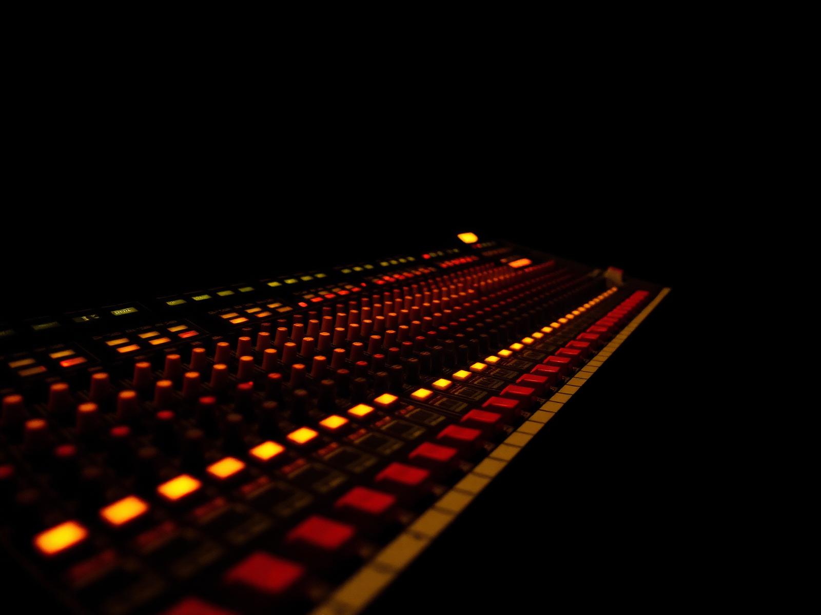 Professional audio mixing console illuminated in a dark studio